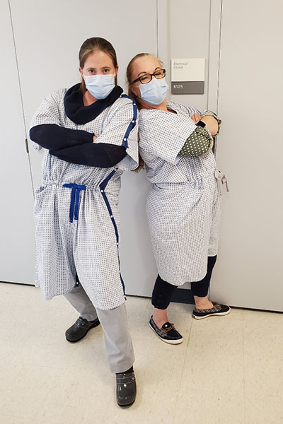 Two masked nurses modeling updated versions of the NewGown™
