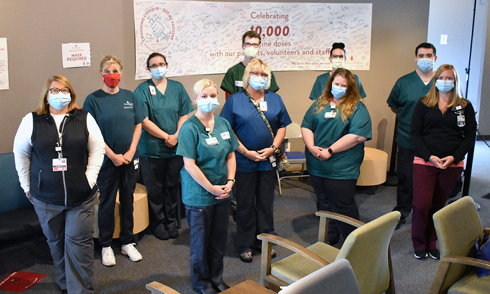socially distanced group of men and women wearing masks and standing in a classroom