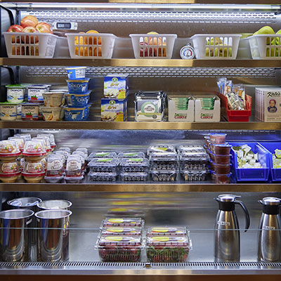 a refrigerated food cooler with various fruits, yogurts and dairy products on display